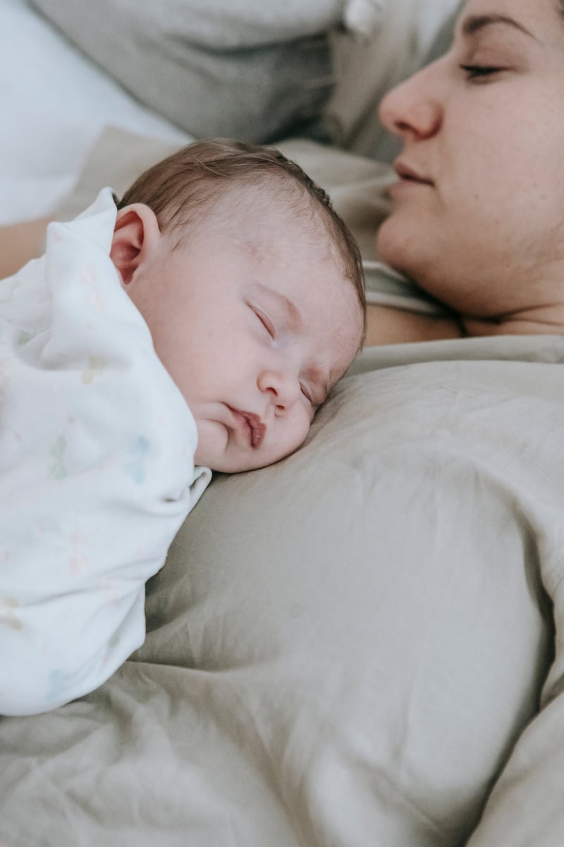 Sleeping mother and baby on bed